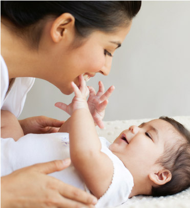 Mother talking to baby as he reaches for her.